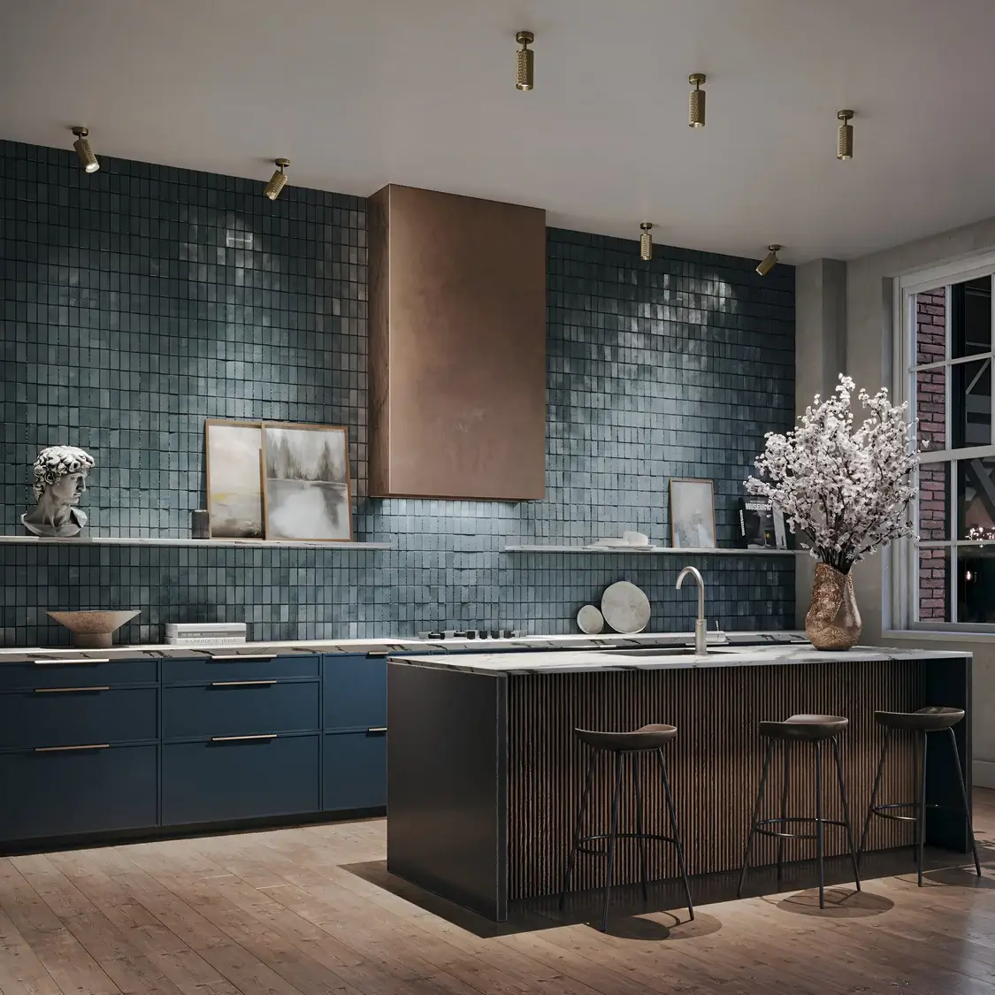 A chic kitchen with textured teal tiles and a central island in a black and wood finish. Brass spotlights highlight decor elements, including framed art and a tall vase with white blossoms.