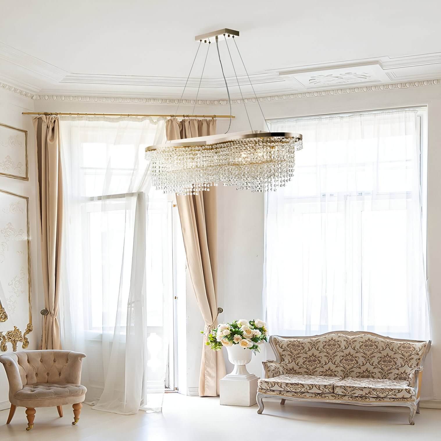 Oval crystal chandelier suspended in a high-ceilinged salon with French drapes and classic mouldings.