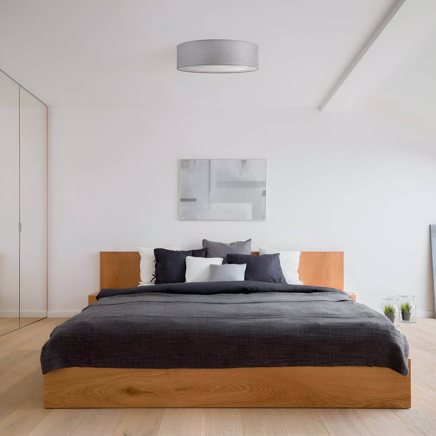 Grey fabric drum flush mount ceiling light in a minimalist bedroom.
