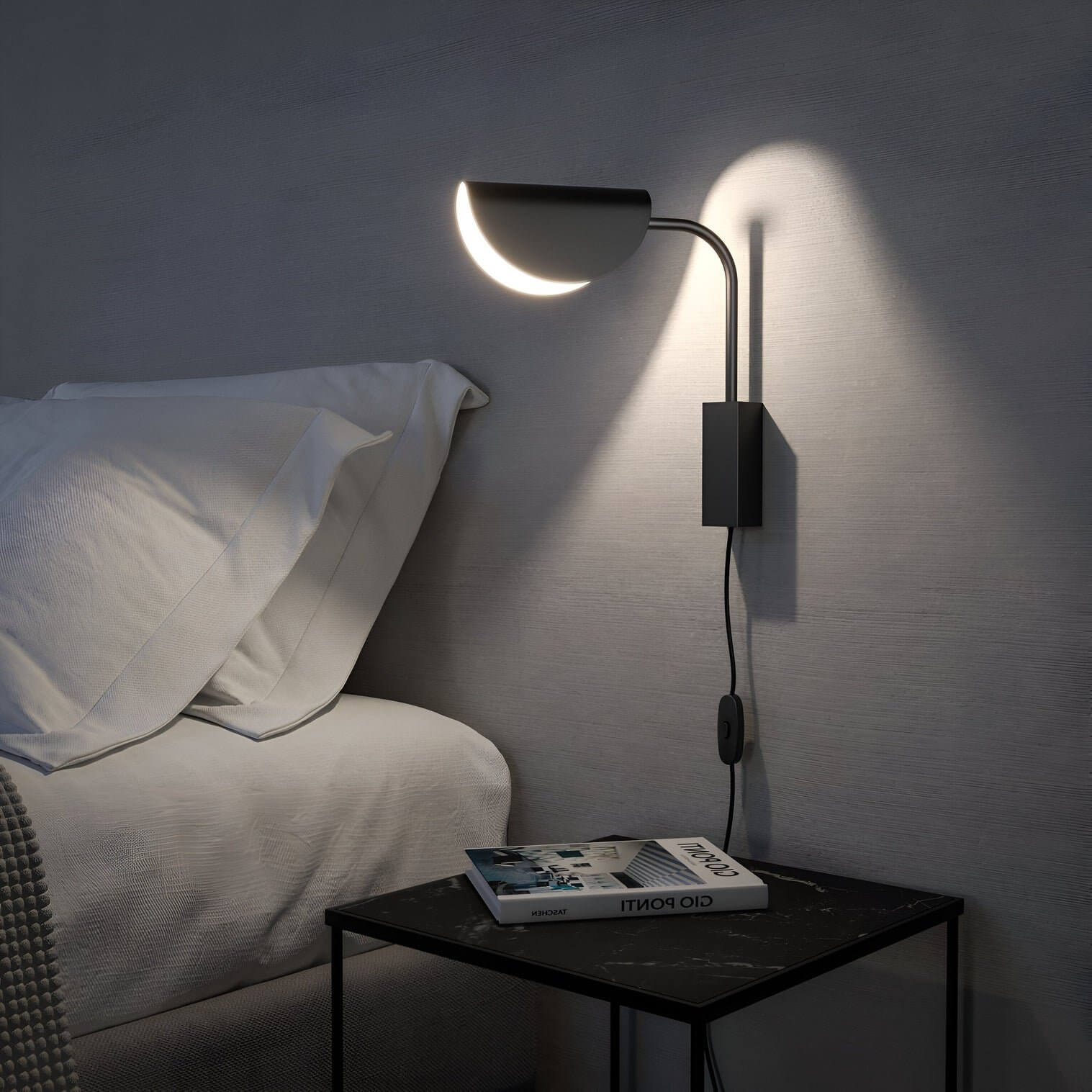 Modern bedroom with black half-dome wall lamp, grey wall, white bedding, and black marble bedside table holding books.
