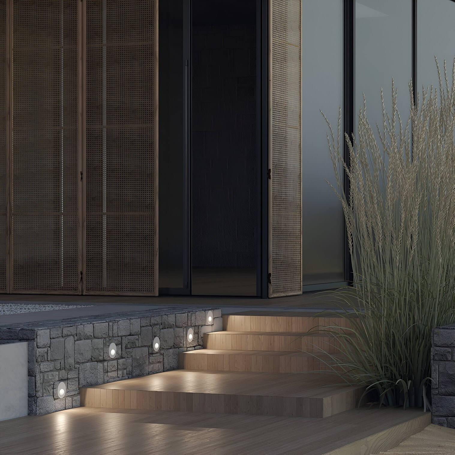 Stone wall with round recessed step lights illuminating wooden stairs leading to a modern home's entrance.