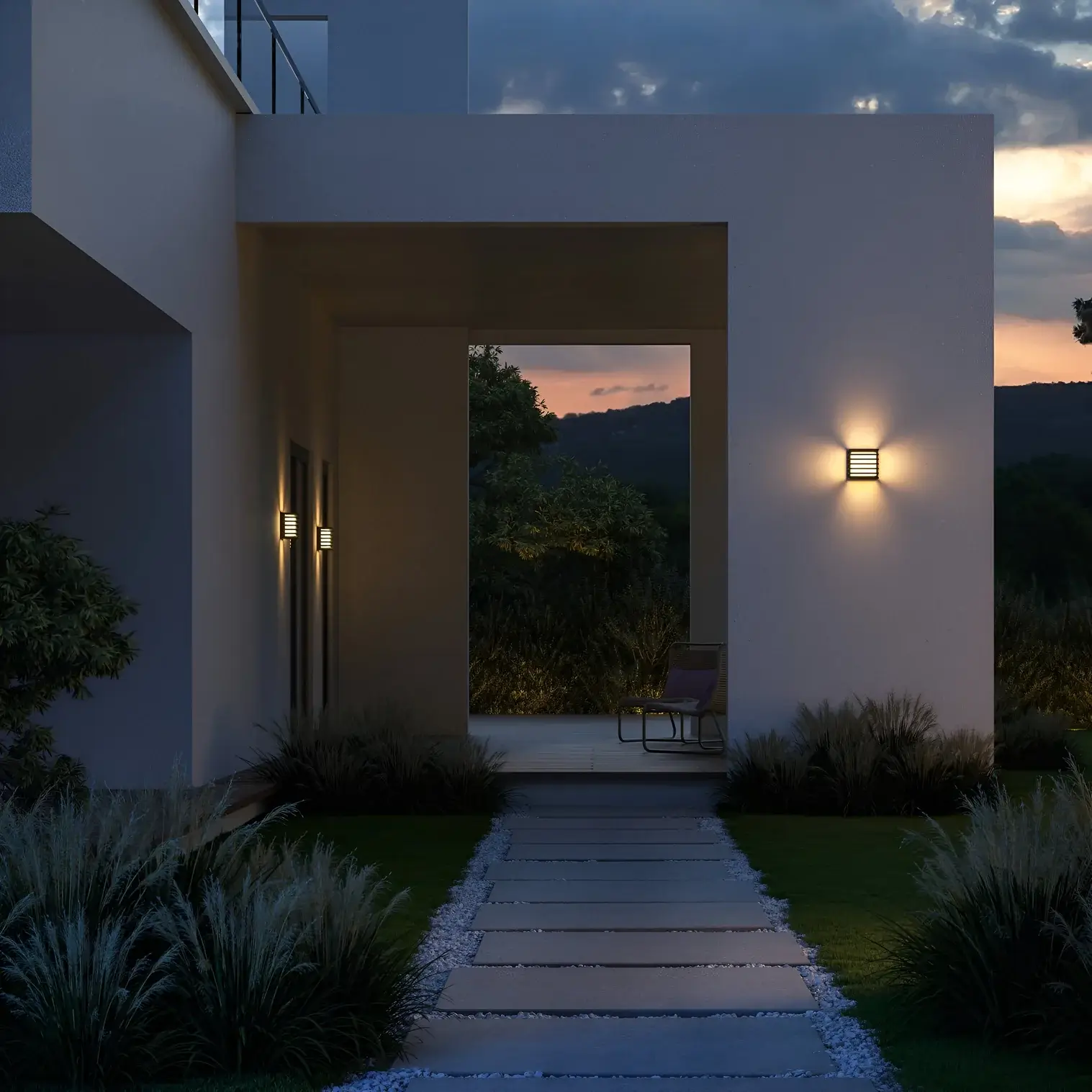 Modern entrance pathway with glowing wall sconces casting light on white walls and neatly trimmed grass at twilight.