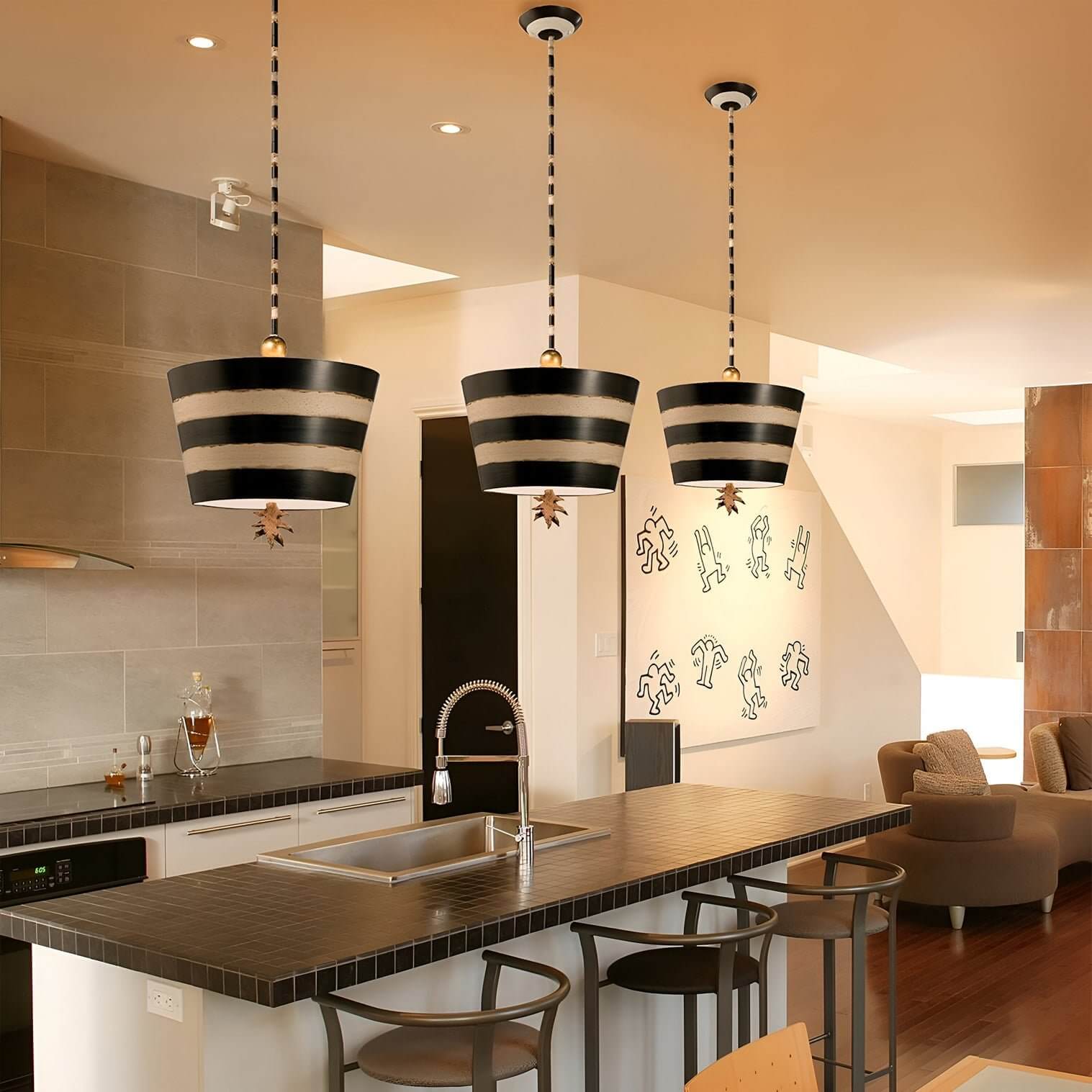 Trio of bold black and gold striped pendant lights over a modern kitchen island.