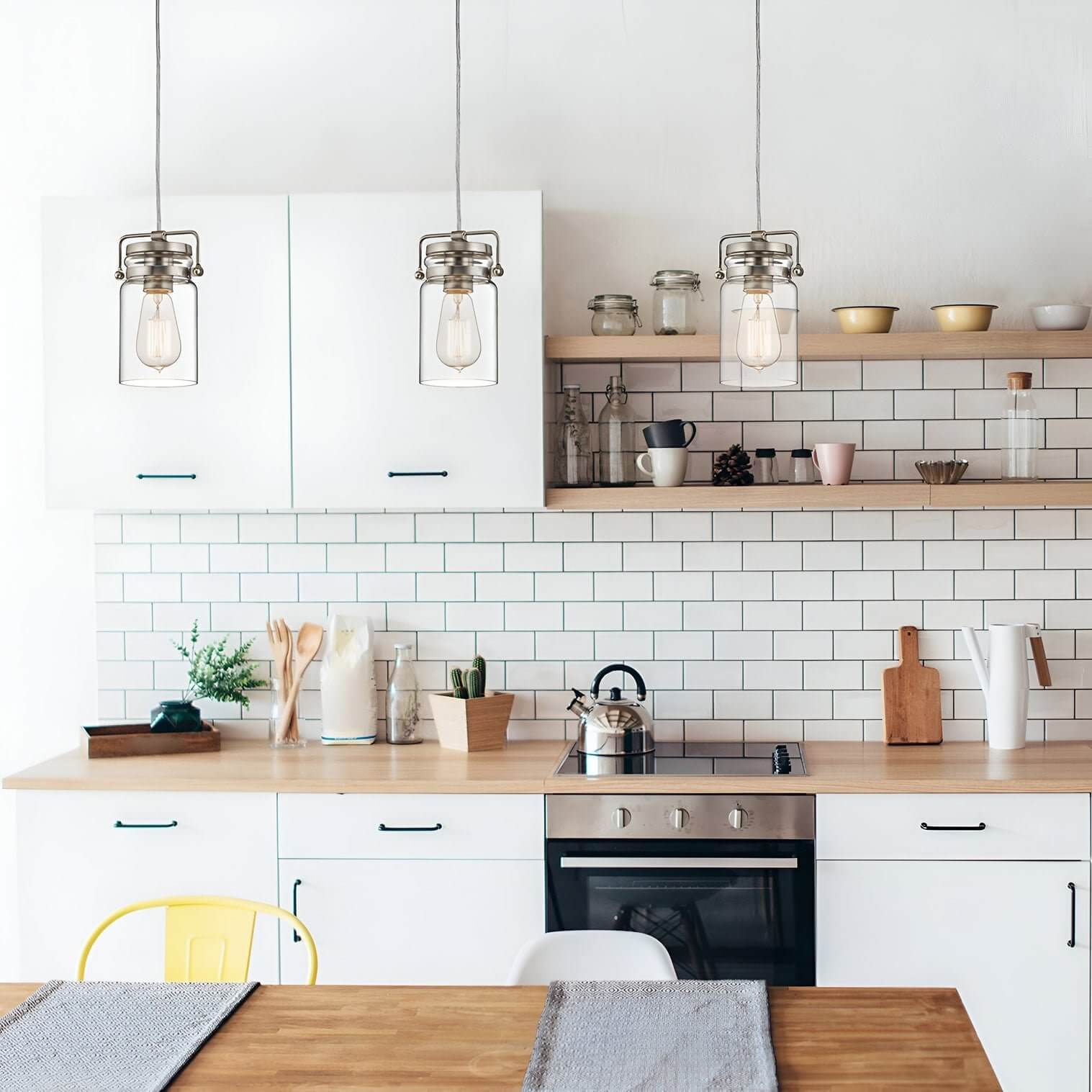 Industrial glass jar pendant lights with exposed bulbs over a white tiled kitchen.