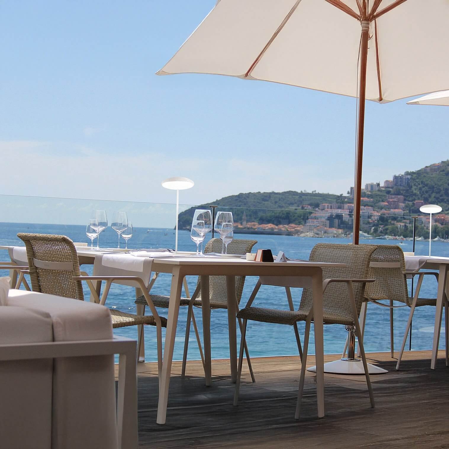 Minimal white disc-shaped table lamps on a terrace overlooking the sea.