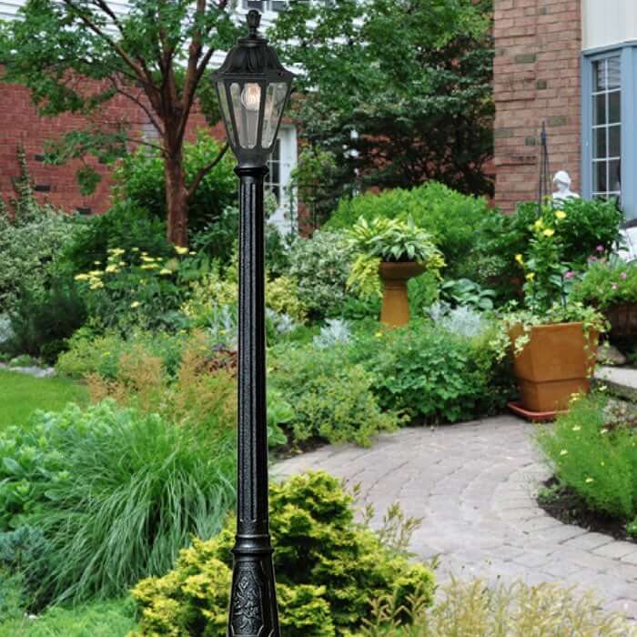 Traditional black garden lamp post surrounded by lush greenery and curved stone path