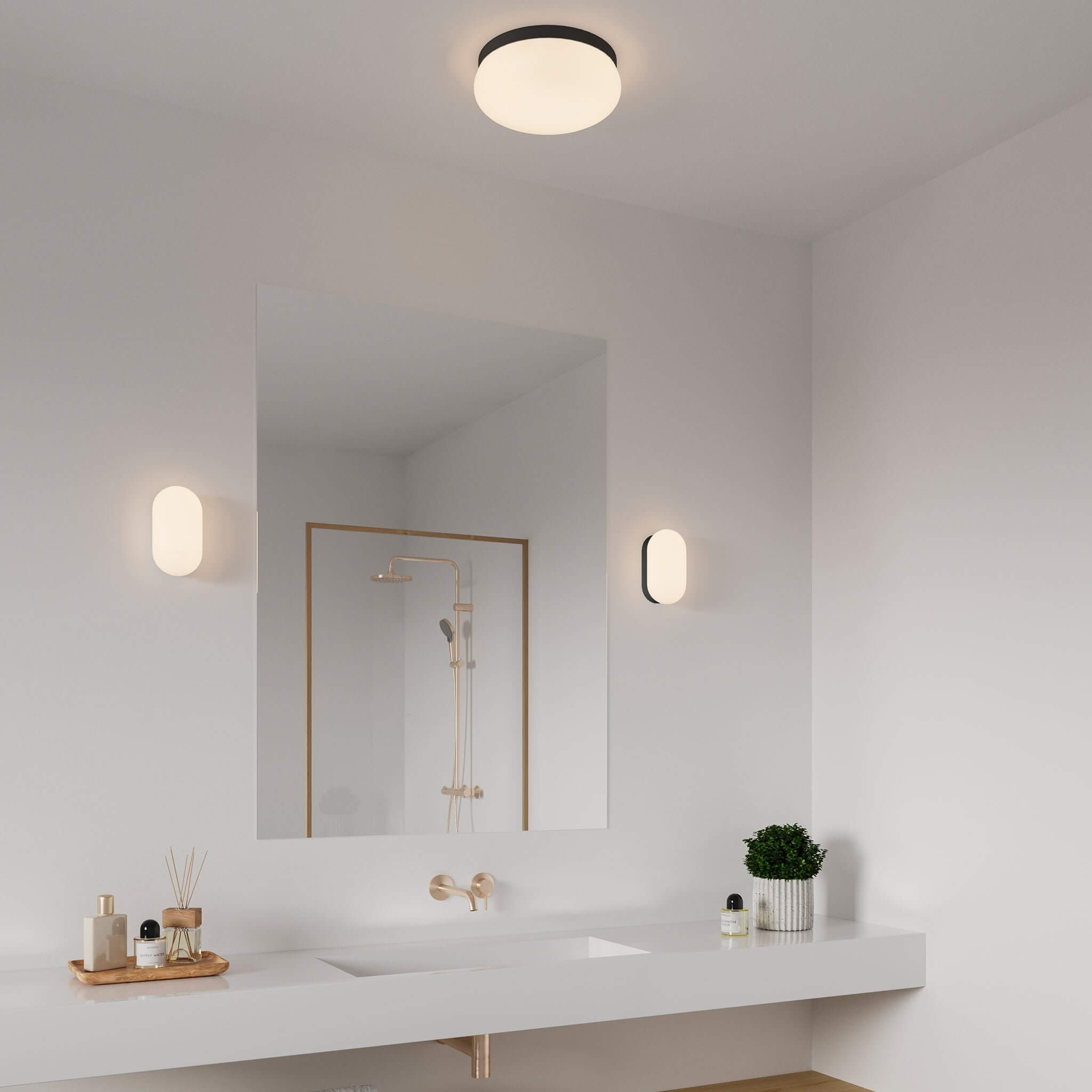 Simple white bathroom with a single mirror, modern black faucets, round ceiling light, and two capsule-shaped wall lights.