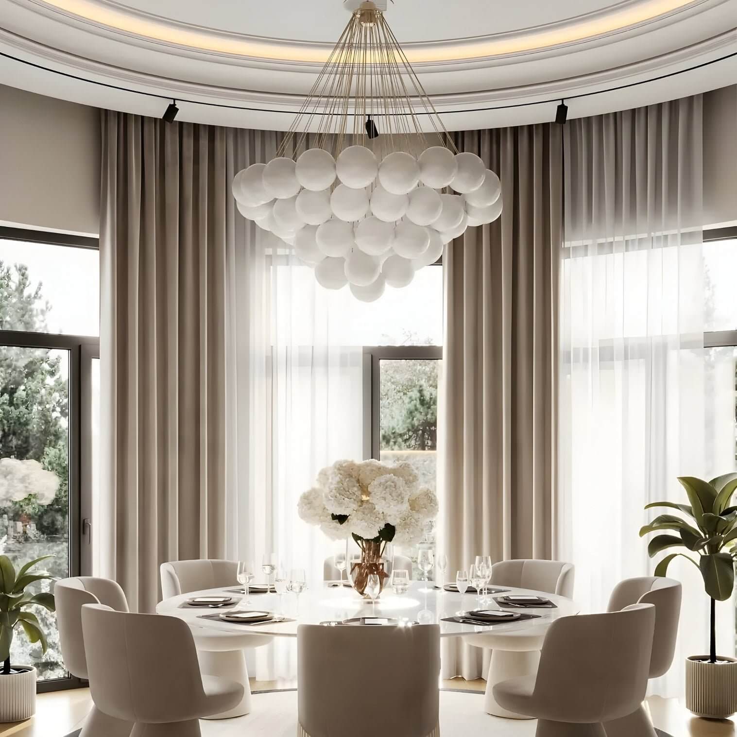 Large cluster chandelier made of white glass spheres suspended above a round table in a curved-window dining room.