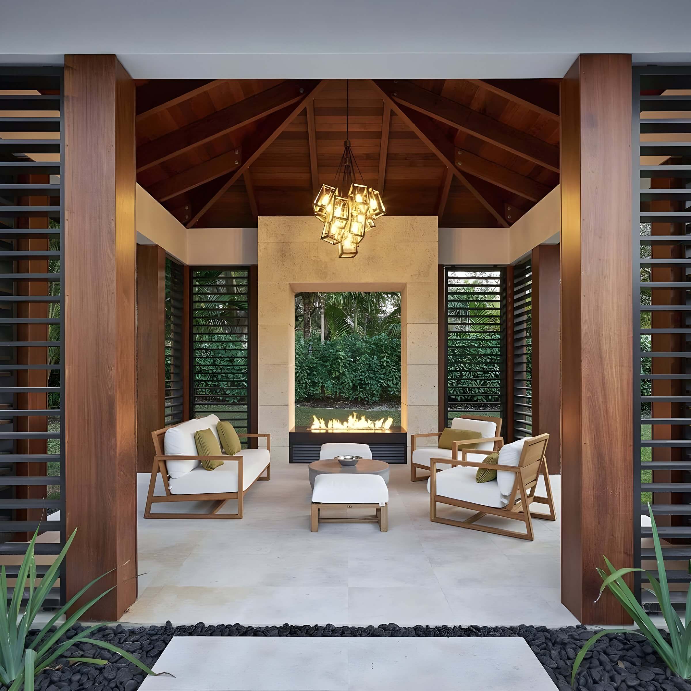 Modern garden pavilion with geometric chandelier, white cushioned lounge chairs, and a central linear fireplace.