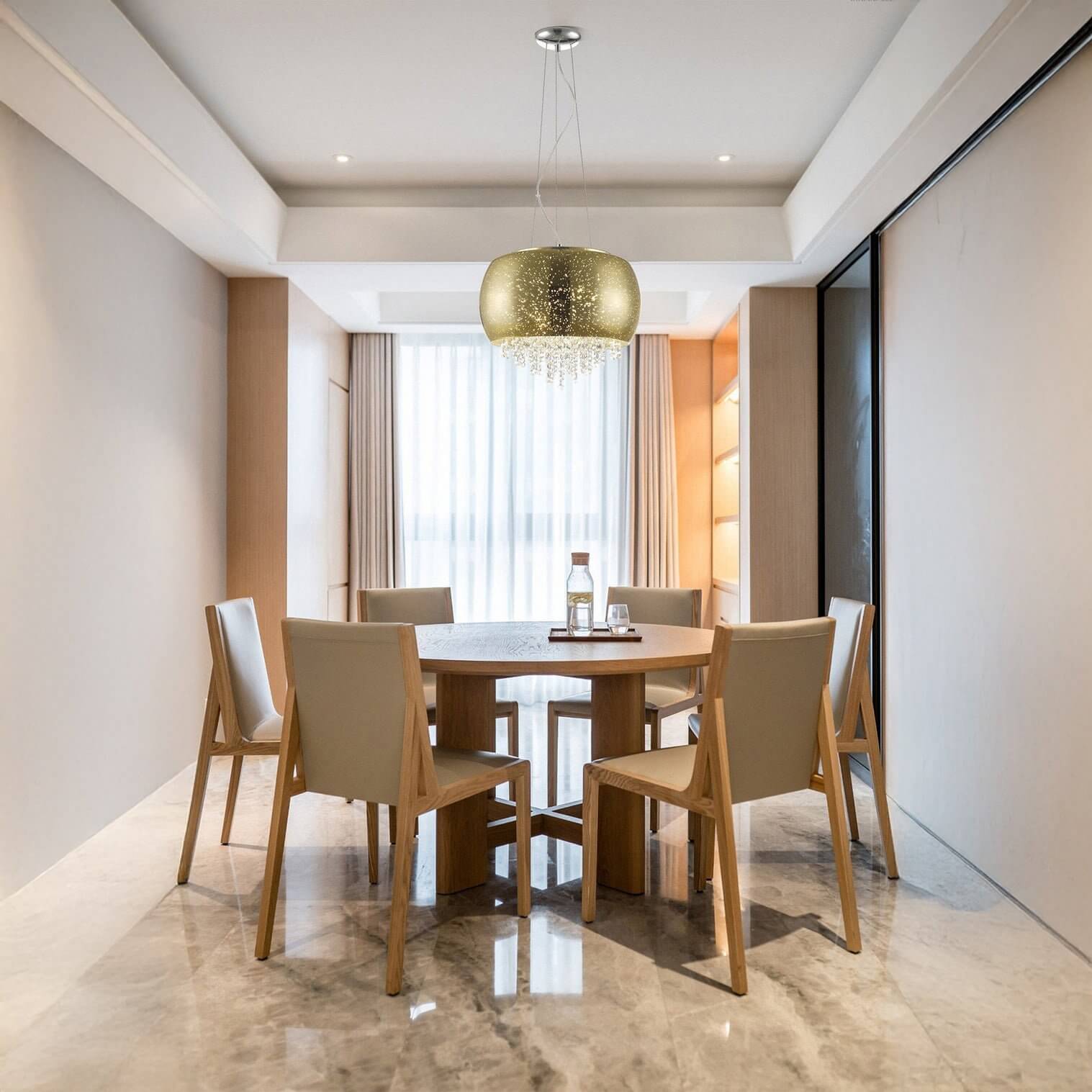 Golden pendant light with crystal accents glowing above a round wooden dining table.