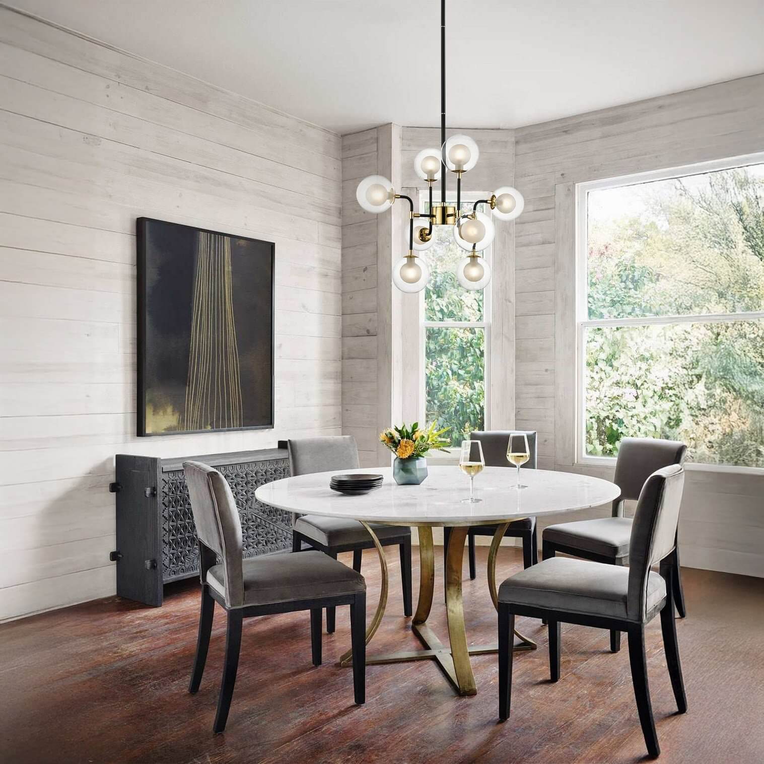 Modern brass chandelier with globe bulbs hanging above a round marble dining table.