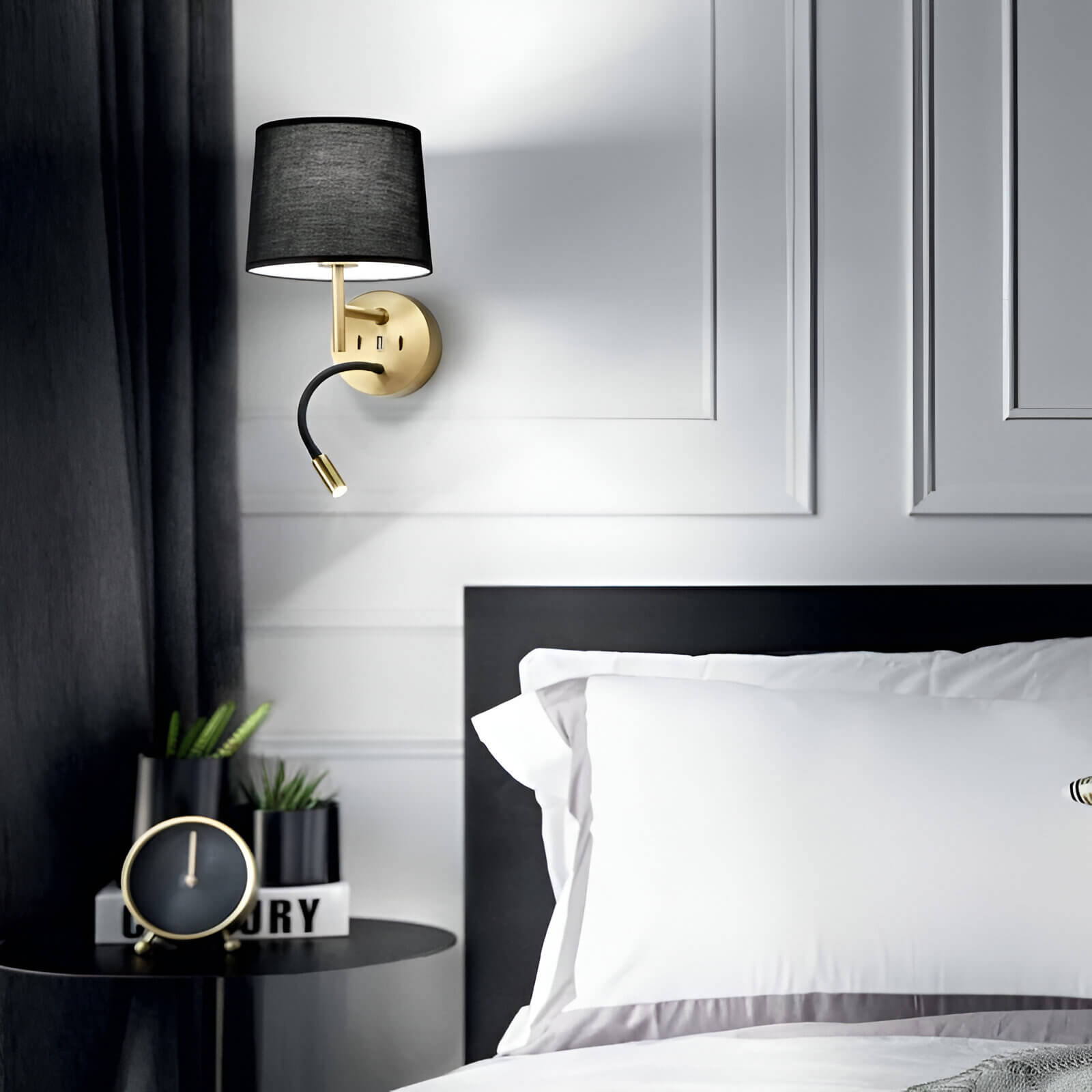 Modern wall sconce with a black shade and brass mount, featuring a reading light arm, ideal for bedside use.