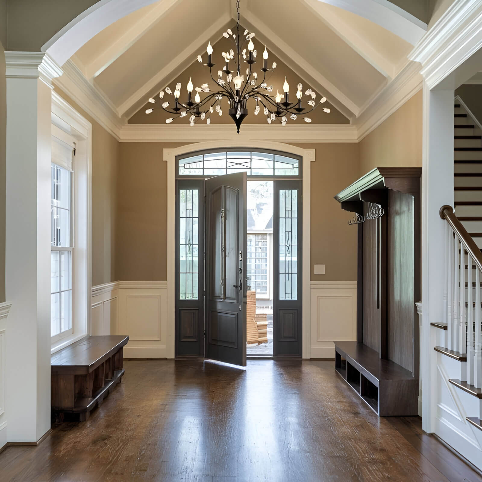 Modern black chandelier with leaf-shaped lights in a tall entryway with vaulted ceiling.