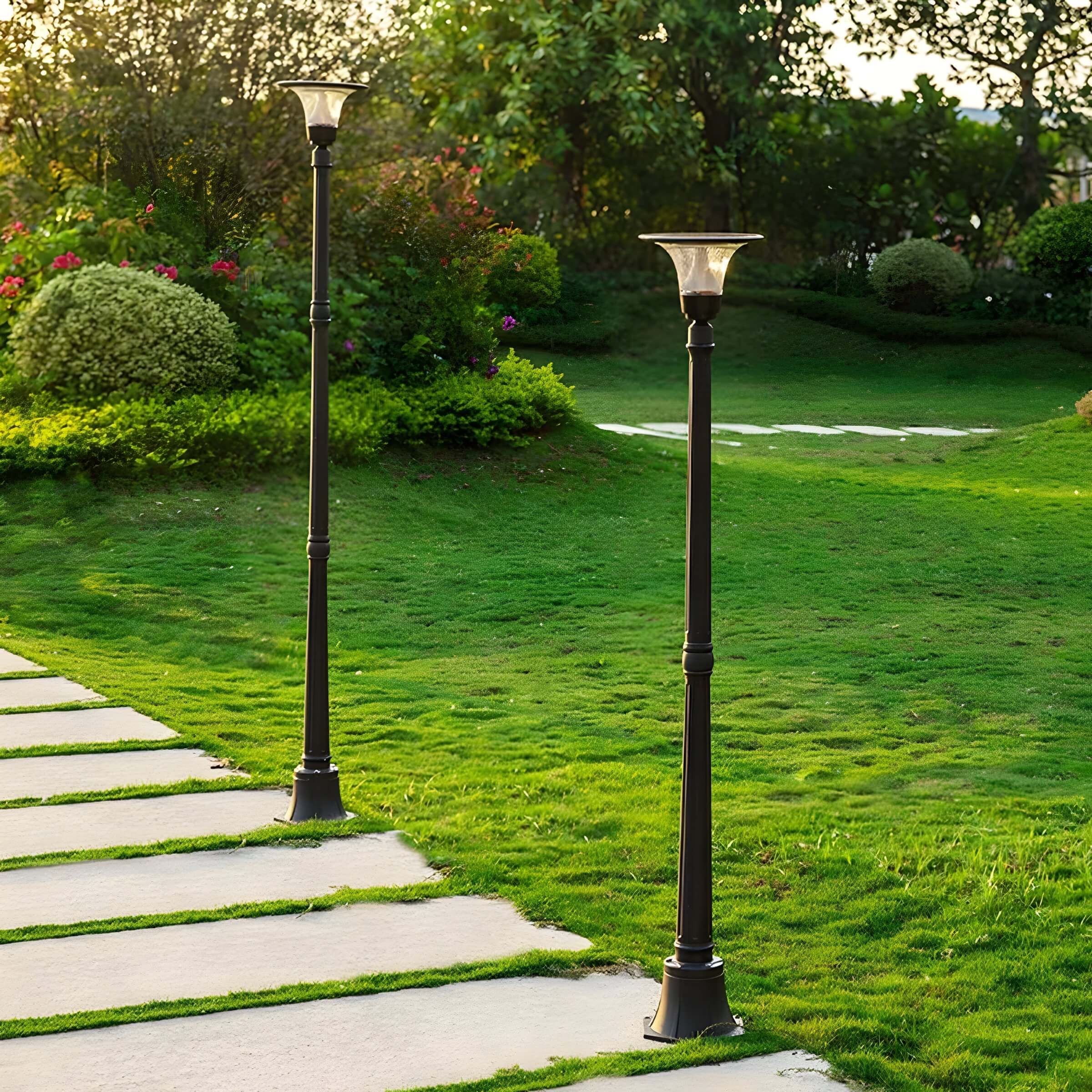 Twin black path lights lining a green lawn with concrete stepping stones at golden hour.