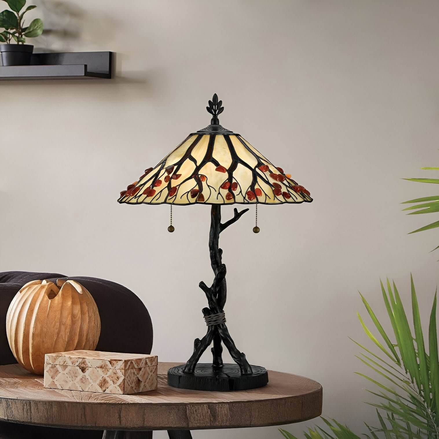 Tree-trunk base table lamp with cherry blossom stained glass shade on a rustic wood table with natural accents