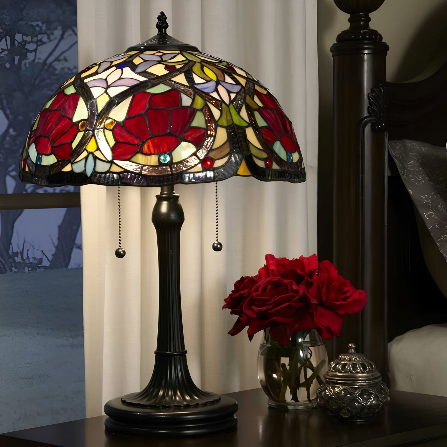 Classic Tiffany-style stained glass table lamp with red floral design beside red roses.