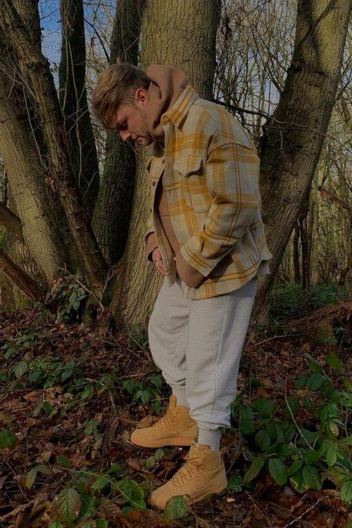 man wearing vintage flannel shirt and sweatpants in the woods