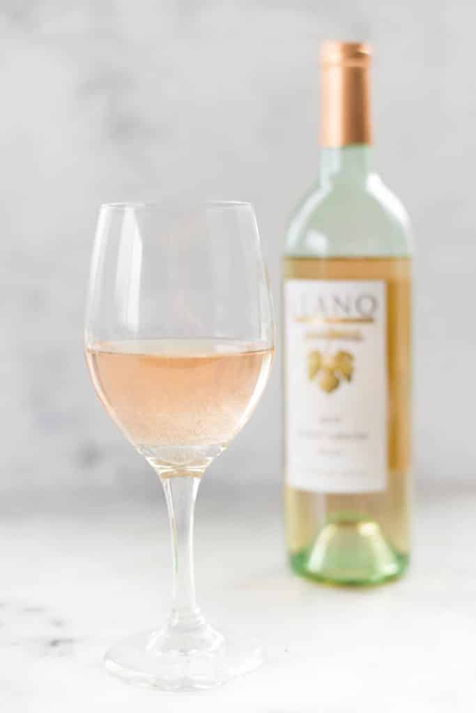 A glass of Llano Estacado Pinot Grigio wine next to the bottle of Llano Estacado Pinot Grigio; alcohol can cause inflammatory processes in the body.