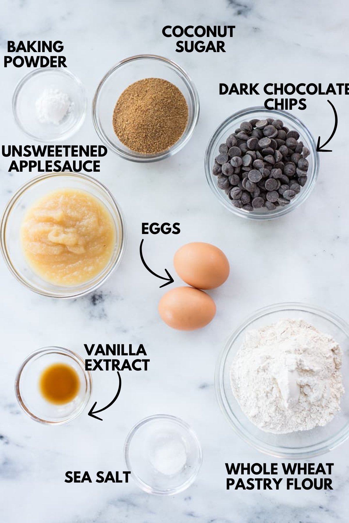 An image of ingredients for healthy dark chocolate brownies laying flat against a white marble surface.
