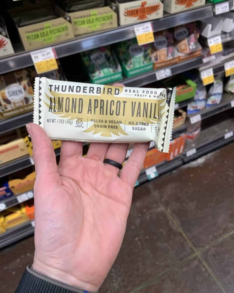 A hand holding a protein bar from the brand Thunderbird.