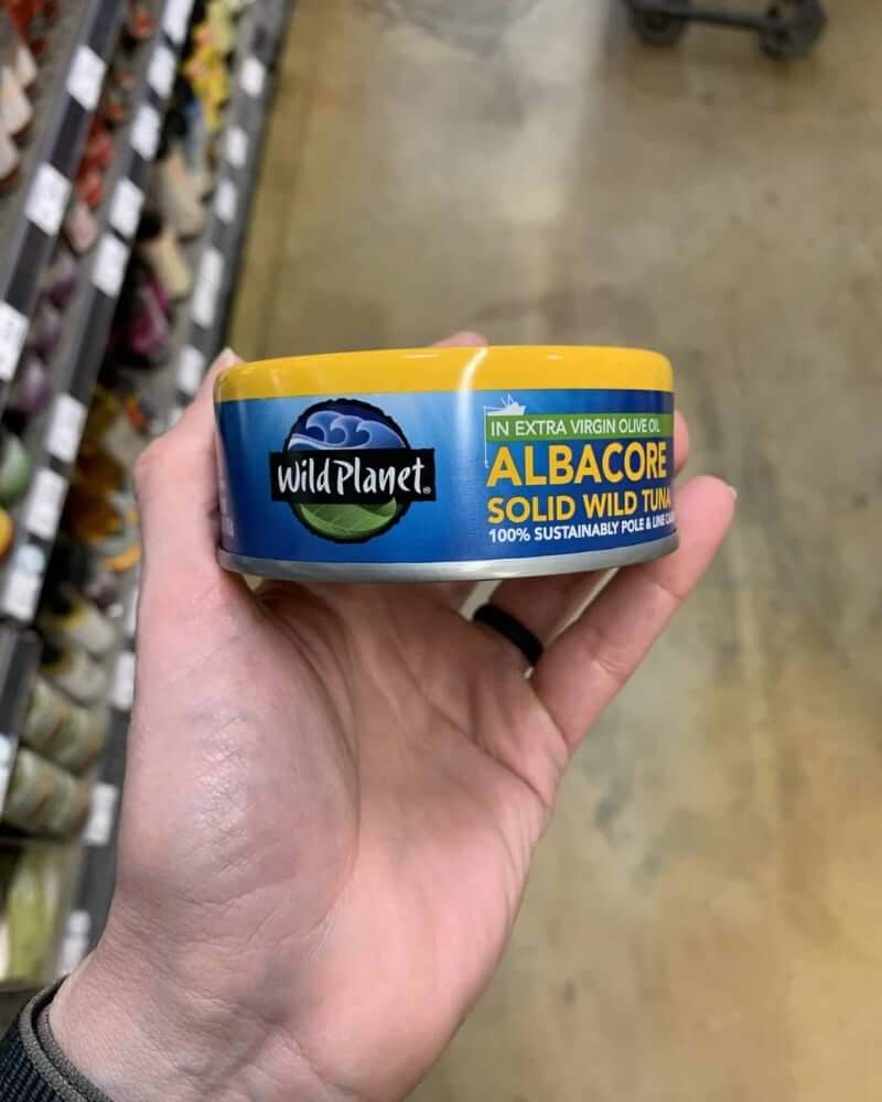 Hand holding a tuna can labeled Wild Planet Tuna.