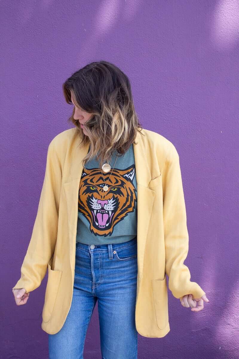 Angela wearing the Thread Hippie Cosmic Tiger women’s graphic tee styled with a mustard oversized blazer and classic denim jeans.