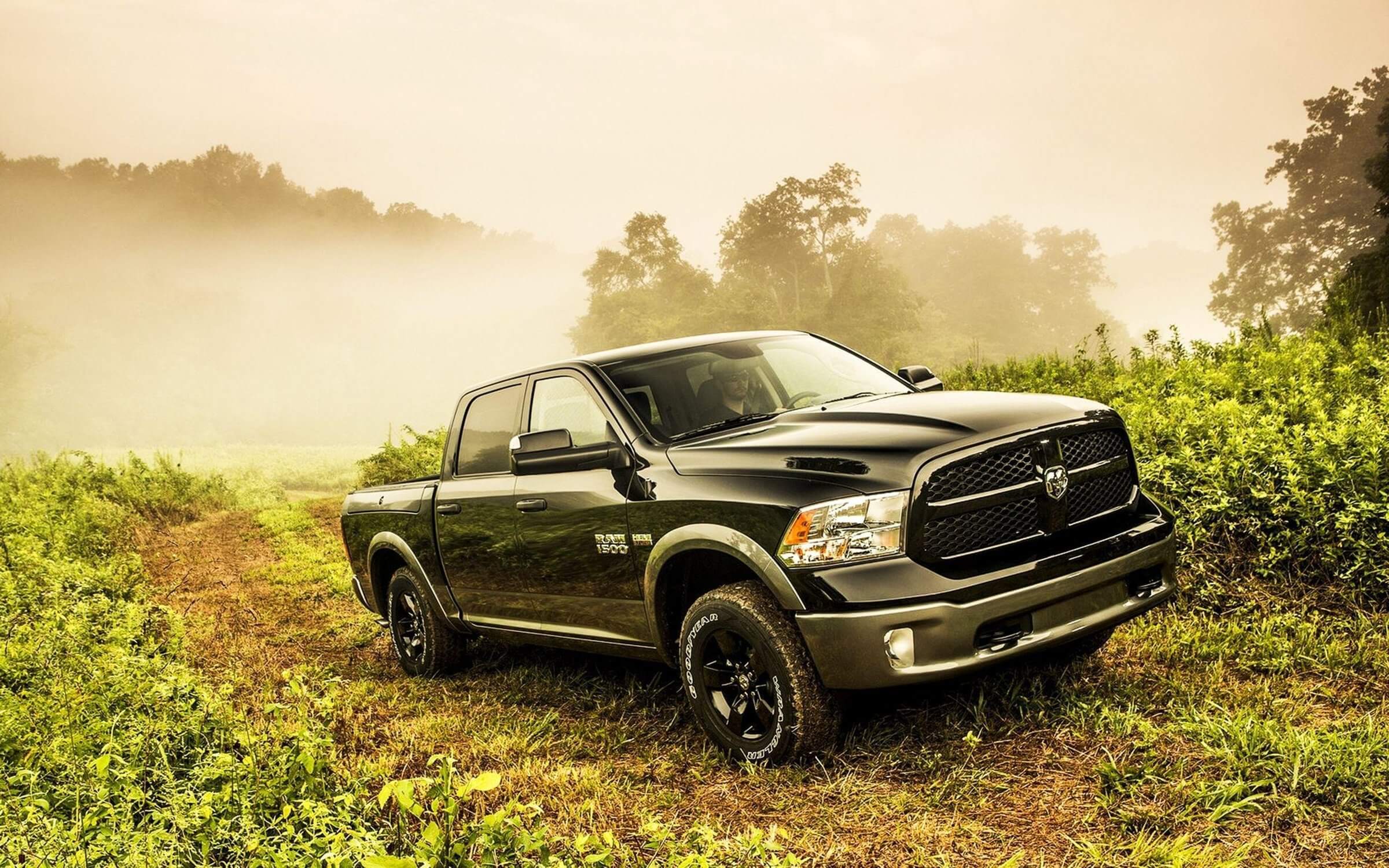 Black Ram 1500 truck, praised for its performance, with adaptive cruise control and crew cab driving though a field.