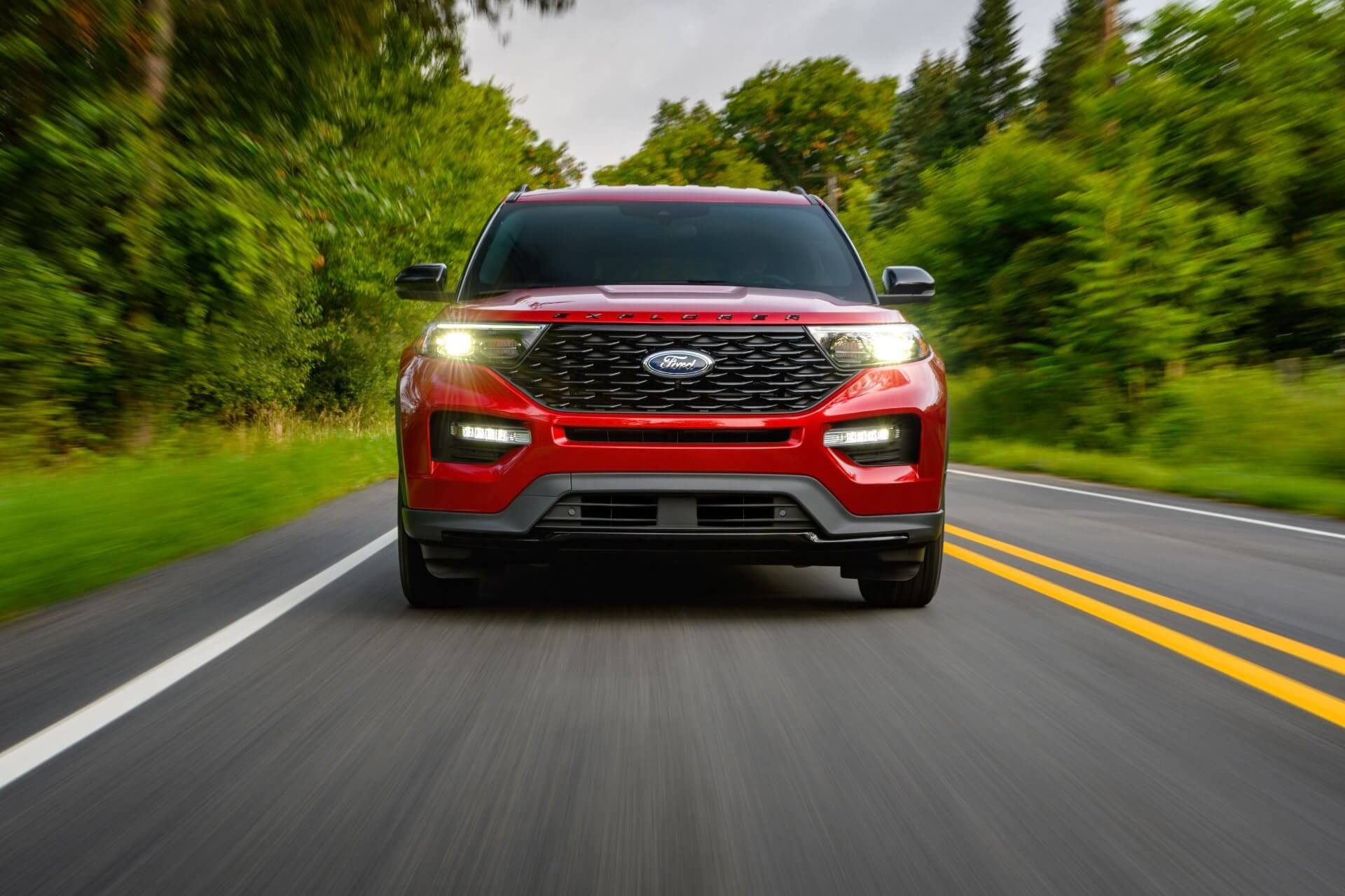 Good condition red Ford 4x4 driving down the road without a human in the photo.