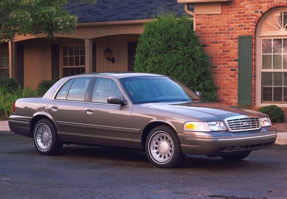 Grey car parked in front of a brick building.