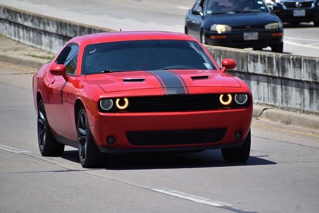 Red Dodge Charger driving on the highway.