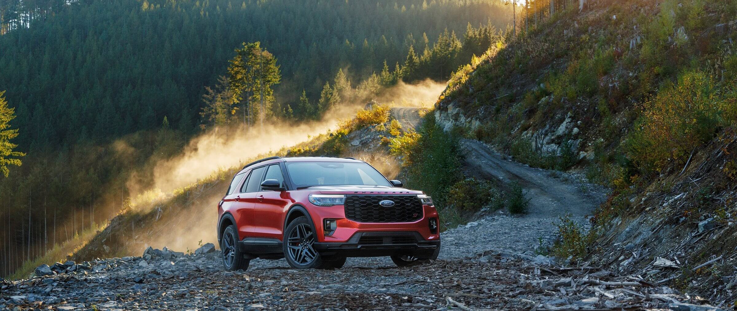 Reliable red Ford Explorer parked in a trail in the mountains, with estimated fuel economy of 21 mpg in the city and 28 mpg on the highway.