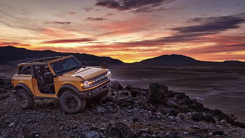 Ford Bronco on a rough terrain at sunset, properly equipped with four-wheel drive.