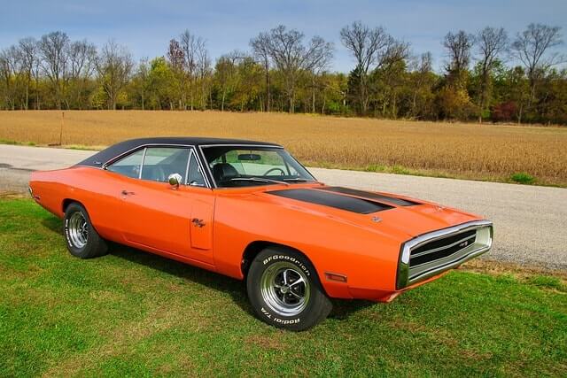 A classic orange Dodge Charger in a field.