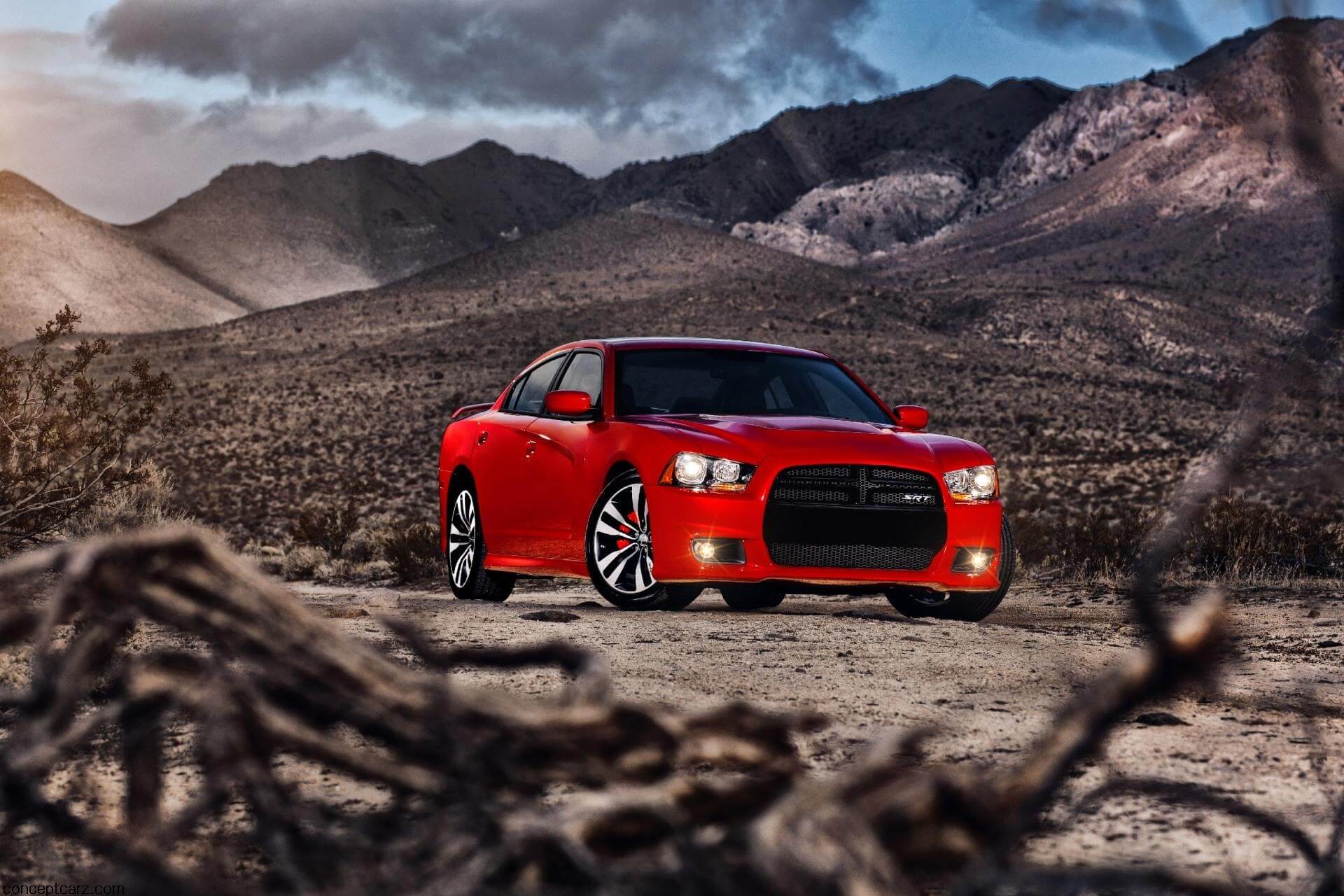Red Dodge Charger parked in a barren environment with a cloudy sky in the background.