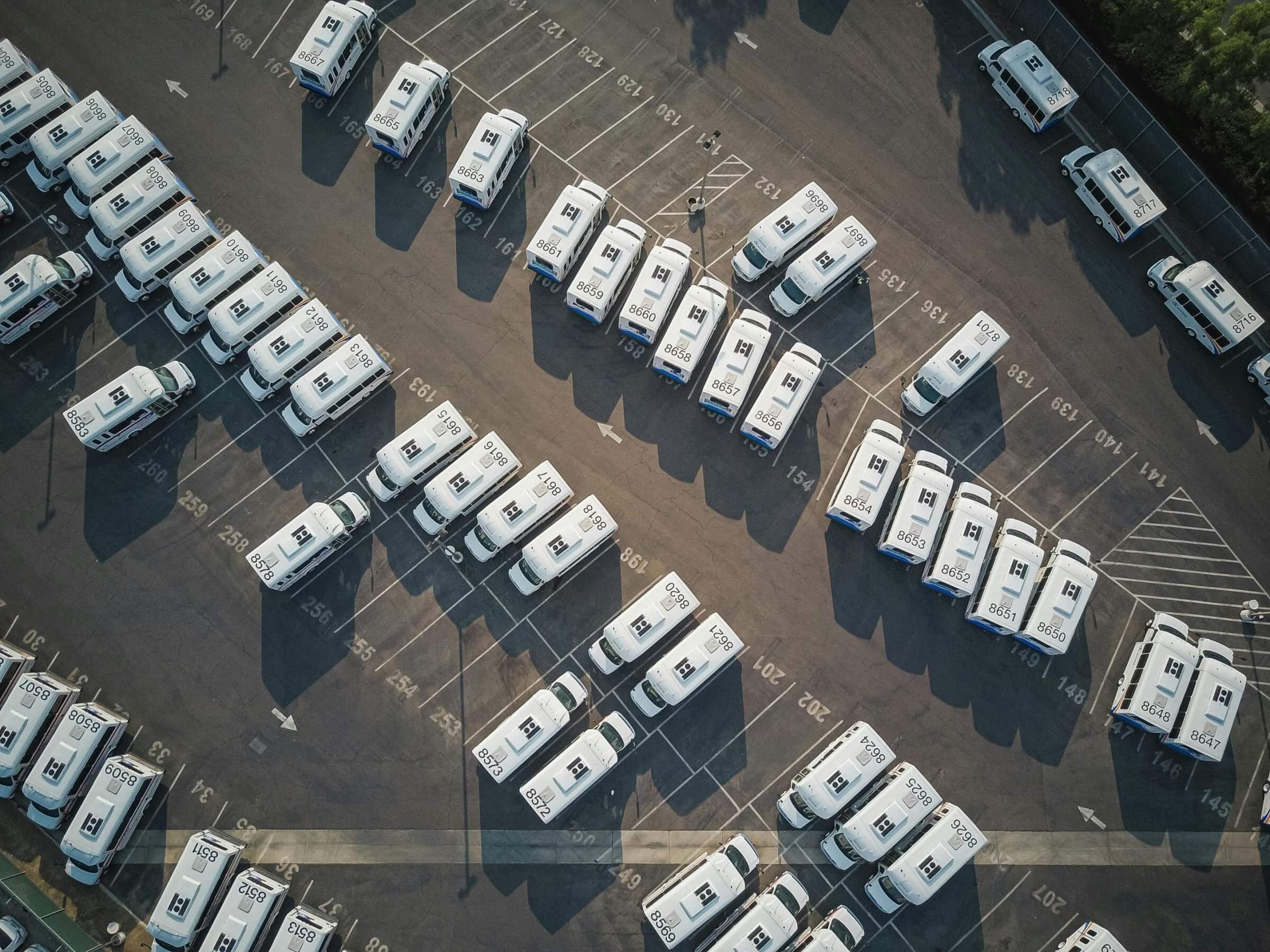 Arial view of parking lot with a fleet of white vehicles.