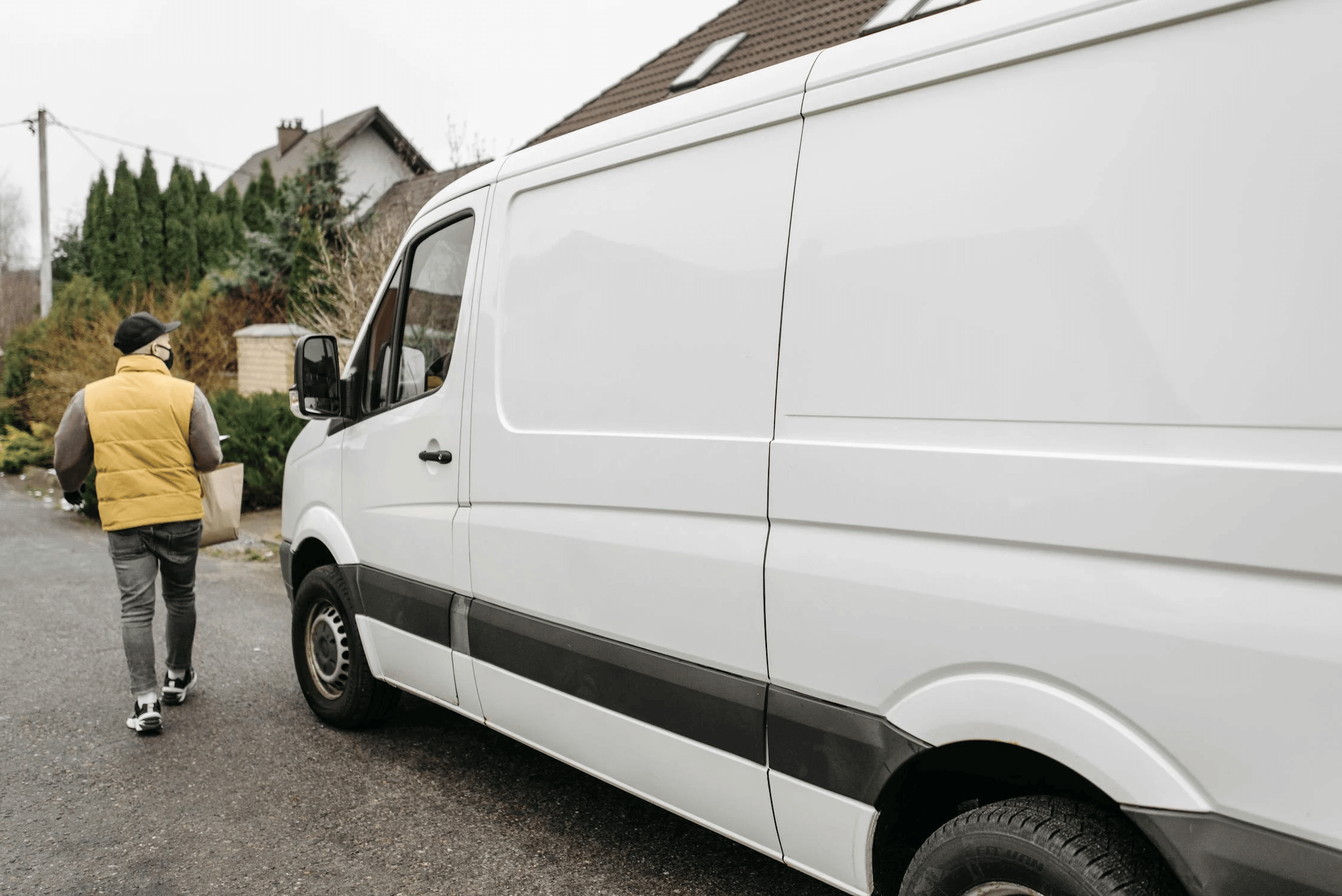 Delivery man carrying box beside parked van.