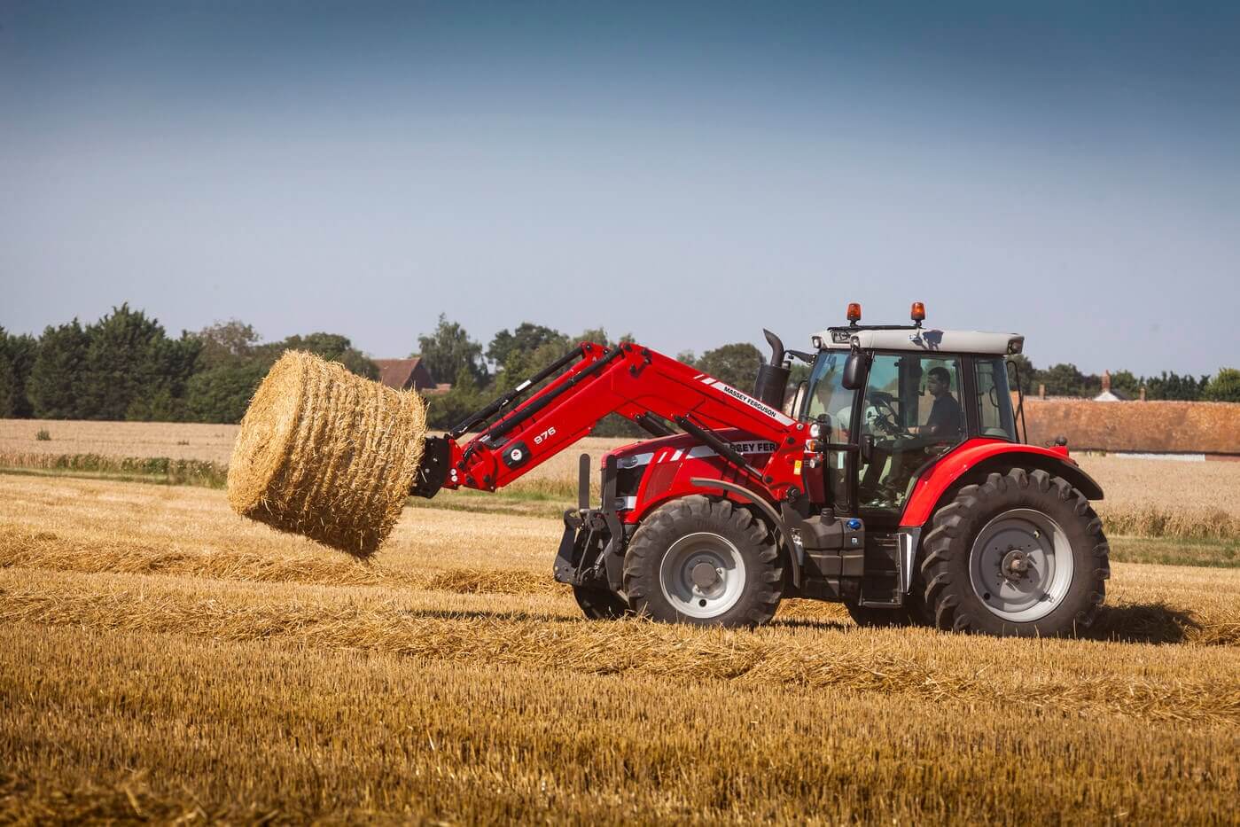 MF 7600 tractor in a hay field making bales.