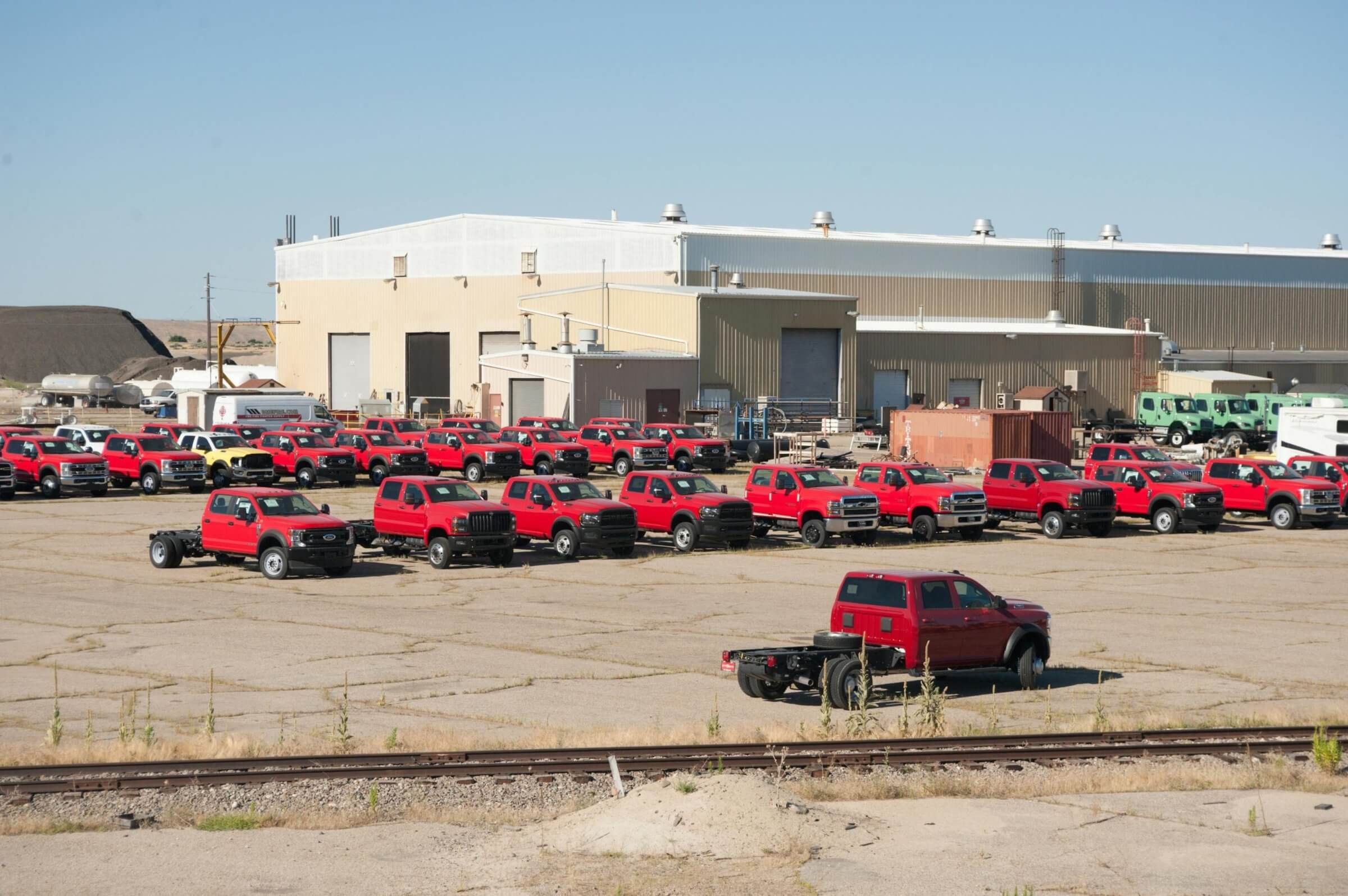 Parking lot full of red trucks used by a company.