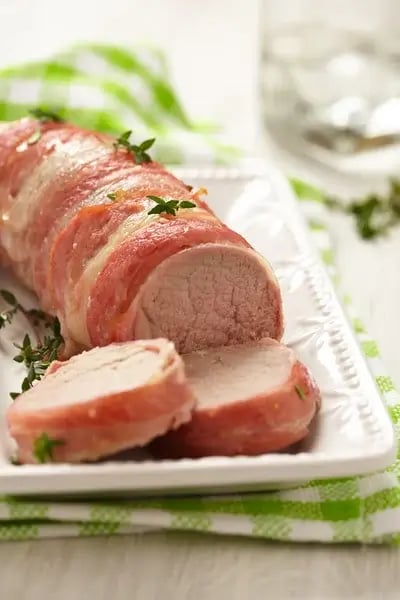 Bacon Wrapped Pork Tenderloin with Honey Glaze Bacon wrapped pork tenderloin with honey glaze sliced and ready to serve