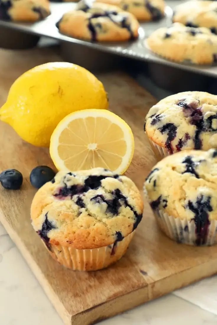 Honey blueberry-lemon muffins with fresh blueberries and lemon on a wooden board