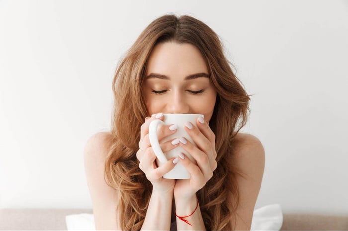 Woman Waking Up and Enjoying Some Coffee After Having a Good Night Sleep on Her SHEEX Performance Bedding