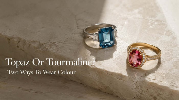 Blue topaz and pink tourmaline fine jewellery arranged on a warm ivory editorial surface