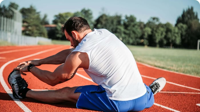 Runner stretching on a track, practicing tendonitis recovery habits before training.