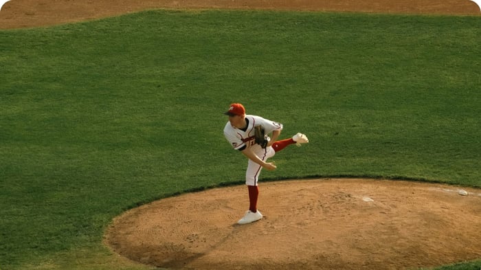 baseball pitcher throwing from mound illustrating what causes tommy john injuries