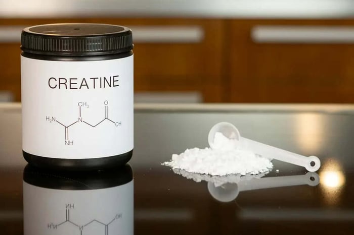 Creatine powder supplement with measuring scoop.