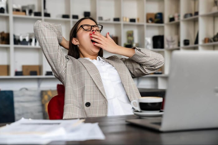 Tired businesswoman yawning at the office desk.