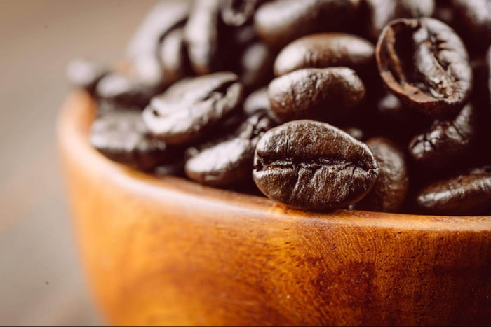 Roasted coffee beans in wooden bowl.