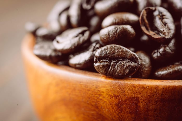 Roasted coffee beans in wooden bowl.