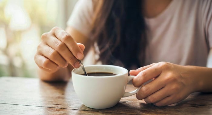 Hands stirring cup of coffee.