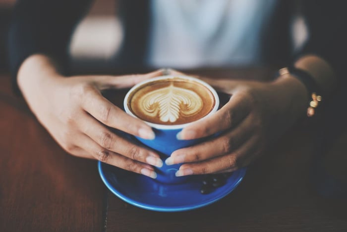 Hand holding a blue cup of coffee